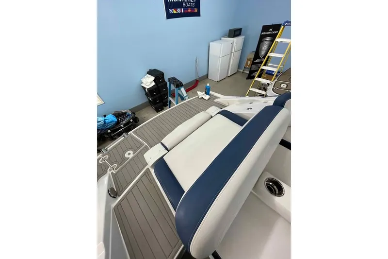 Slide: The Image of 2021 Crownline 255 SS boat interior with blue and white seating in a garage setting. - 3