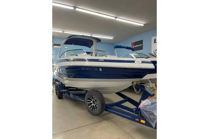 The Image of 2021 Crownline 255 SS boat in showroom, blue and white exterior, on trailer. - 0