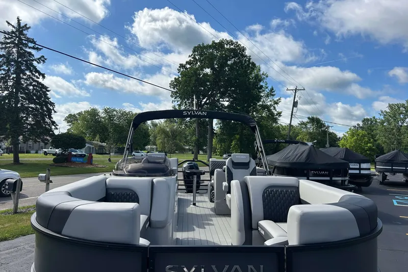Slide: The Image of 2026 Sylvan L3 LZ Tritoon boat with sleek seating, parked outdoors under a blue sky. - 1