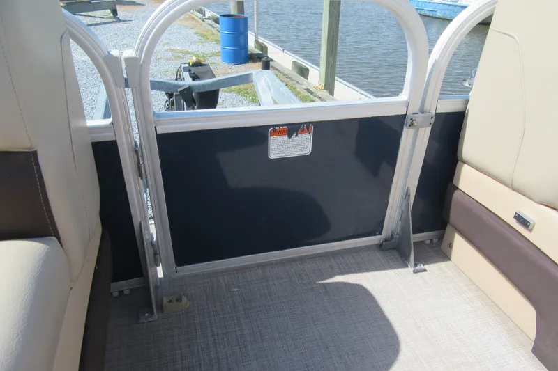 Slide: The Image of 2019 SUNTRACKER 20 DLX PARTY BARGE interior with seating and safety gate by the water. - 15