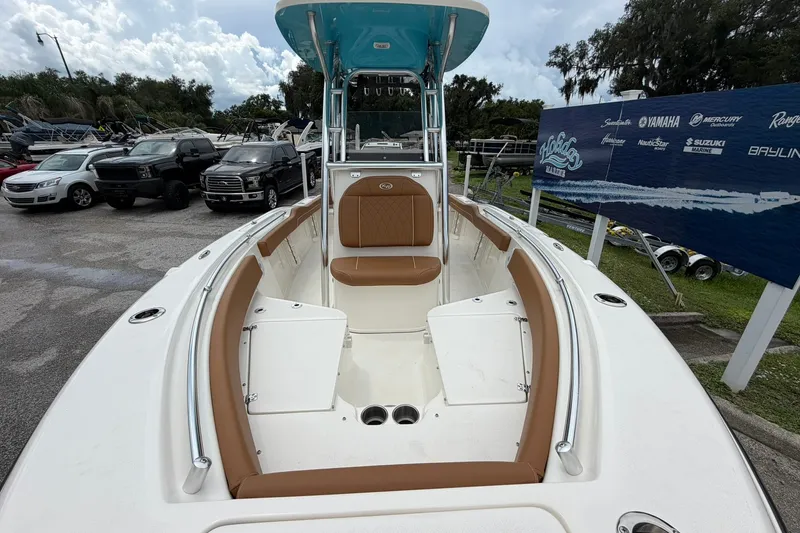 Slide: The Image of 2025 Key West 219 FS boat with tan seating, parked near vehicles and a marine sign. - 16