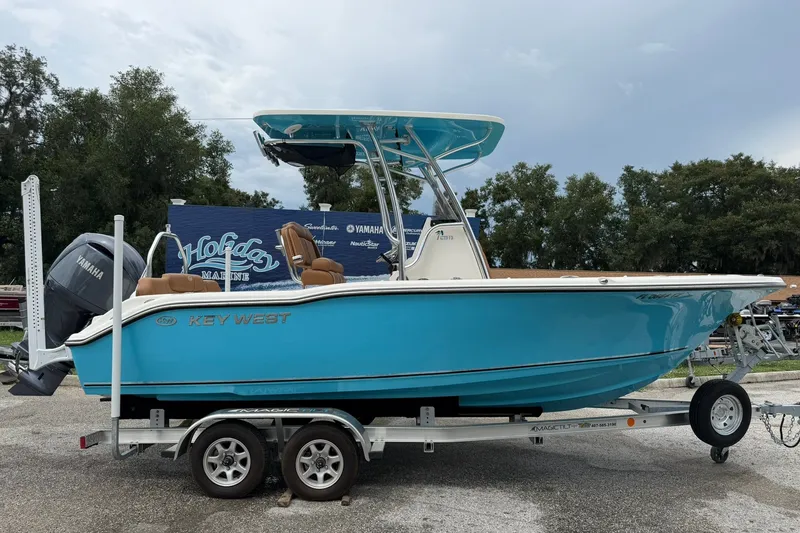 The Image of 2025 Key West 219 FS boat on trailer, vibrant blue hull, Yamaha engine, outdoor setting. - 0