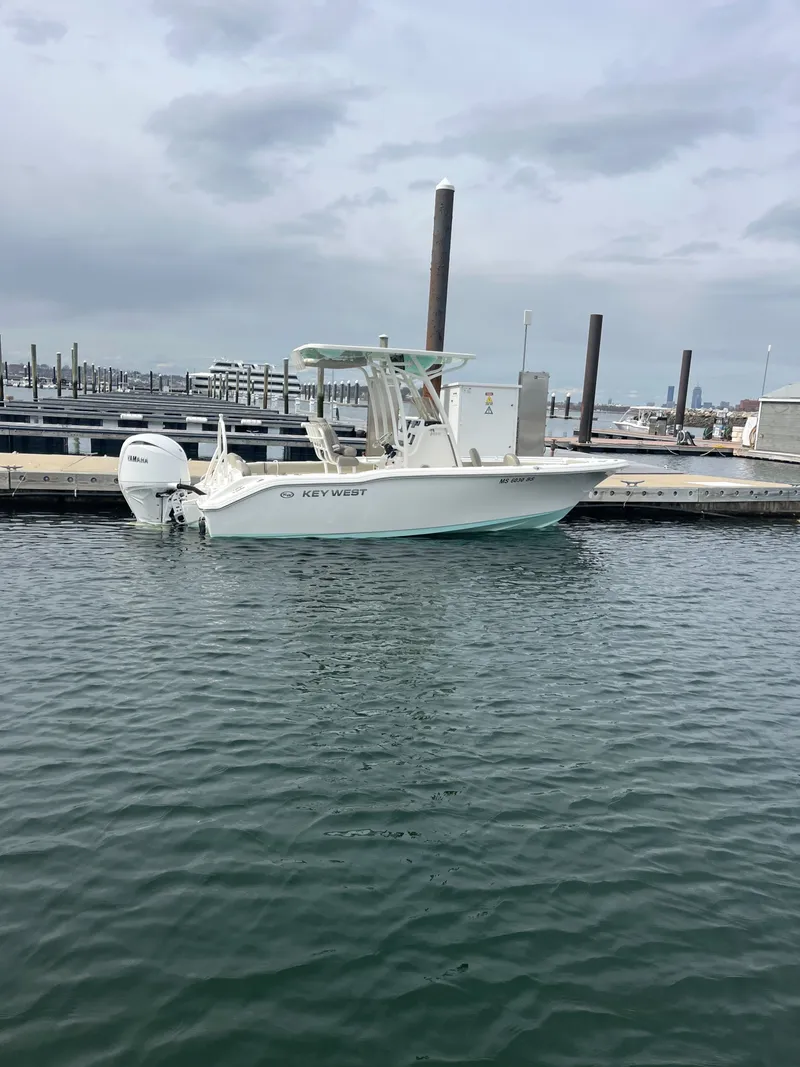 Slide: The Image of A 2024 Key West 219 FS boat docked in calm waters. It features an outboard motor. - 1