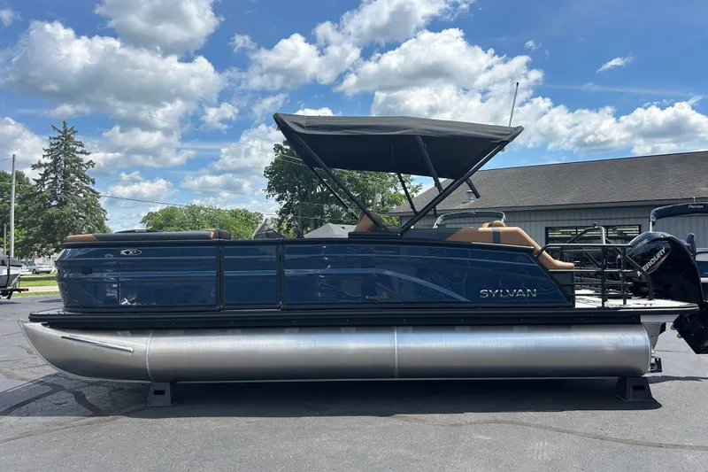 Slide: The Image of 2027 Sylvan X3 LZ DH Tritoon boat with canopy, parked outdoors under a blue sky. - 23
