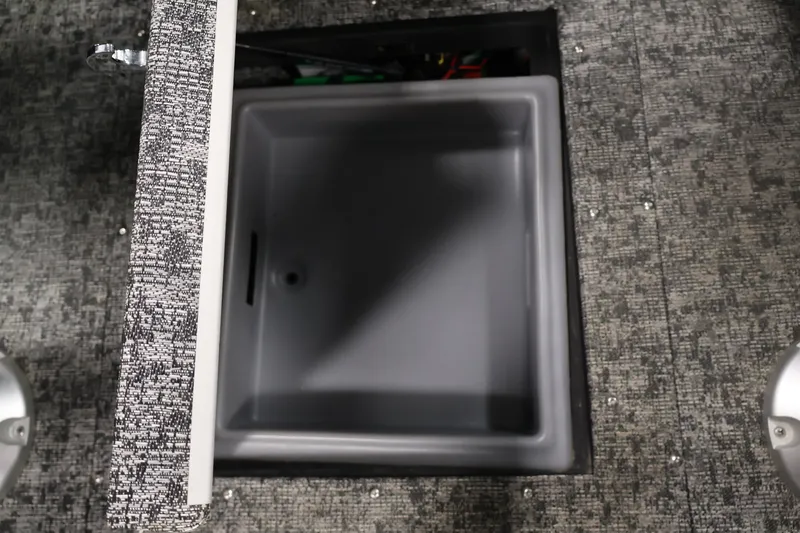 Slide: The Image of 2025 Tracker Targa 18 WT boat storage compartment with open lid on textured flooring. - 34