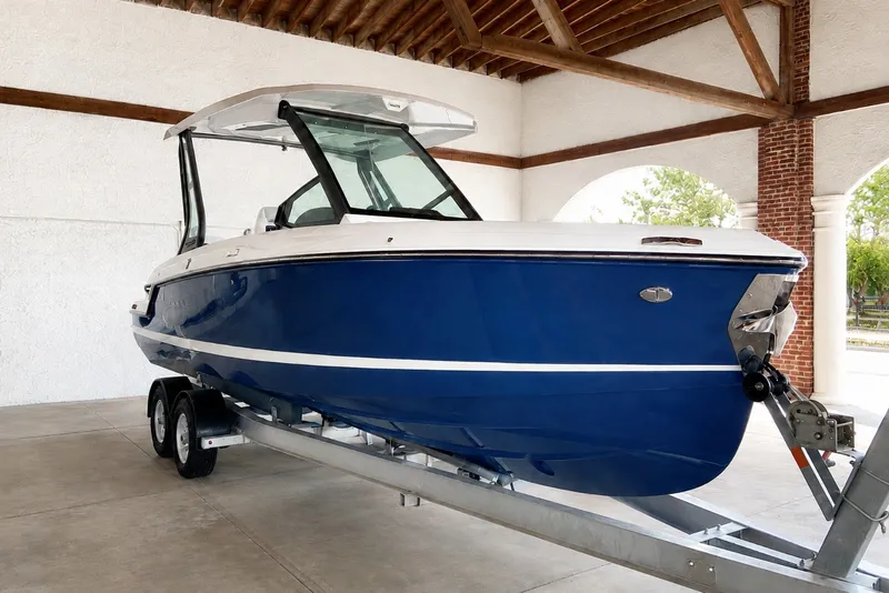 The Image of 2027 Monterey Elite 25 OB boat in blue on a trailer, under a wooden roof. - 0