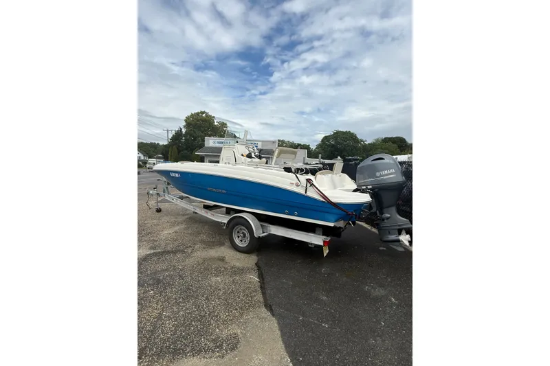 Slide: The Image of 2019 Stingray 206 CC boat on trailer with Yamaha outboard motor, parked outdoors. - 3