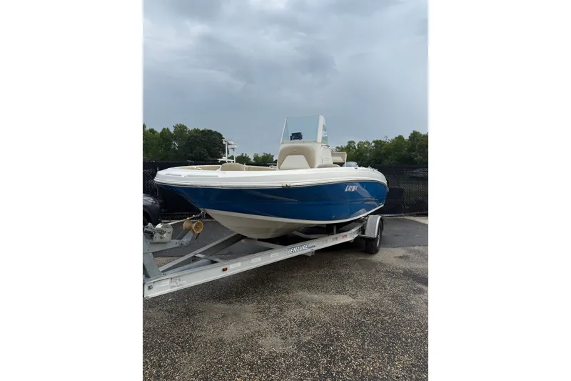 Slide: The Image of 2019 Stingray 206 CC boat on trailer, blue and white design, parked outdoors. - 2