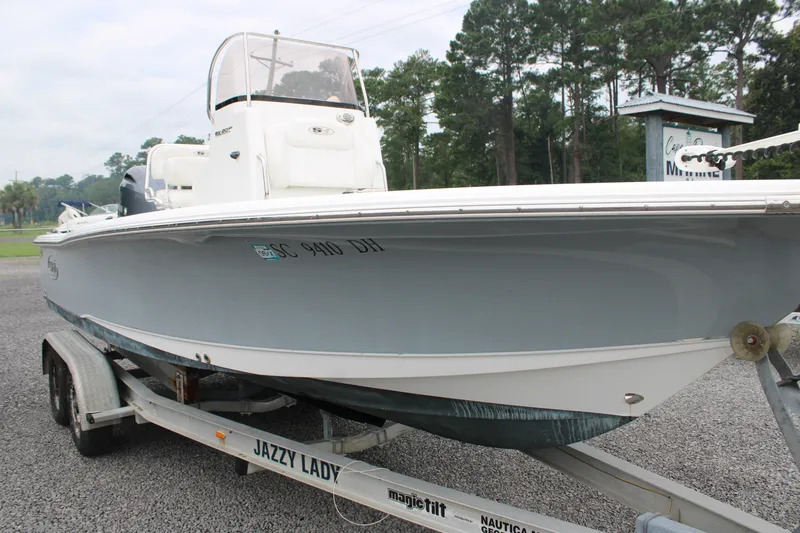 Slide: The Image of 2018 Sea Hunt BX21 boat on trailer, parked outdoors with trees in background. - 2