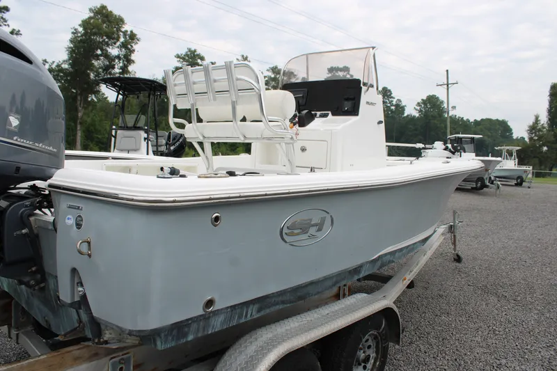 Slide: The Image of 2018 Sea Hunt BX21 boat on trailer, parked outdoors with trees in background. - 9