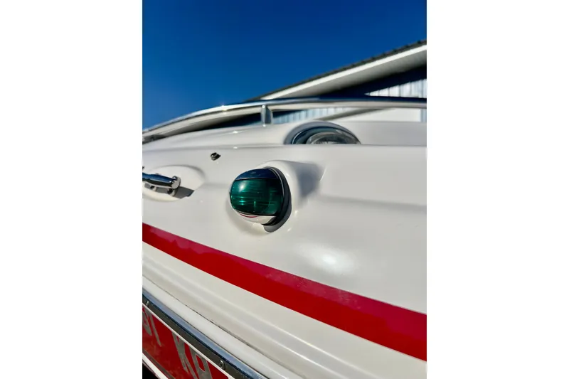 Slide: The Image of 2013 Hurricane SunDeck 2200 OB boat detail with green navigation light and red stripe. - 69