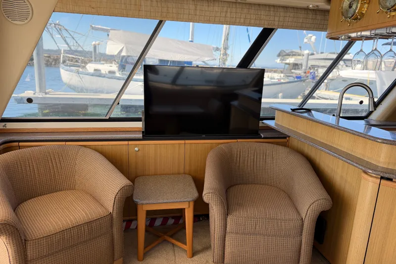 Slide: The Image of Interior of 2000 Bayliner 4788 Pilot House Motoryacht with chairs, TV, and marina view. - 31
