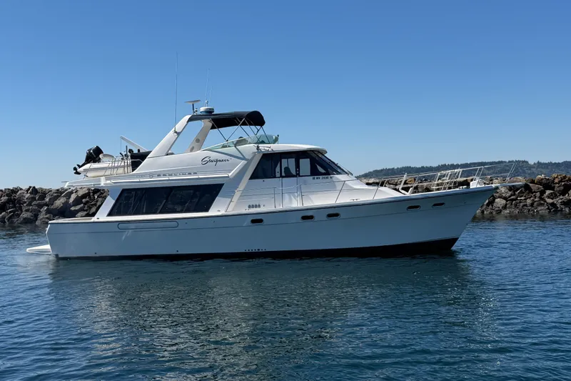 The Image of 2000 Bayliner 4788 Pilot House Motoryacht on calm water, clear sky background. - 0