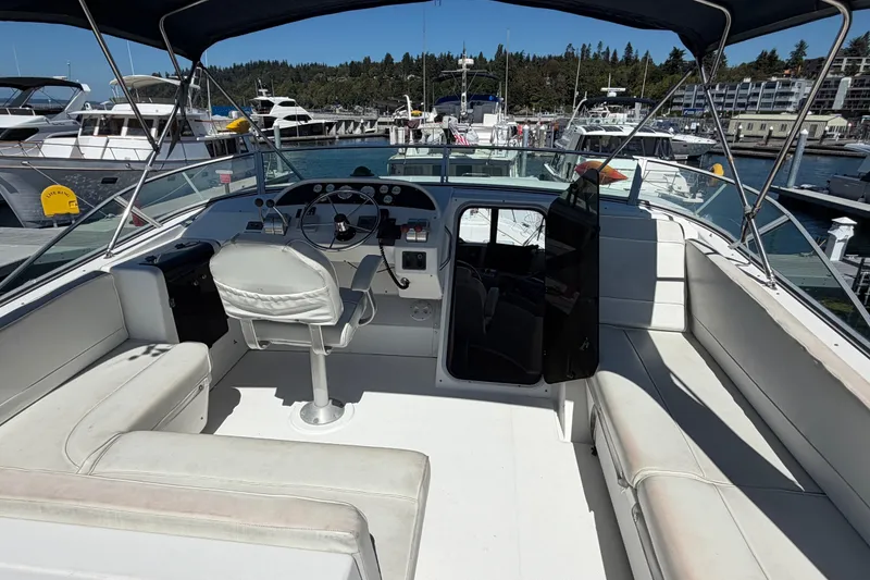 Slide: The Image of 2000 Bayliner 4788 Pilot House Motoryacht interior with helm, seating, and marina view. - 18
