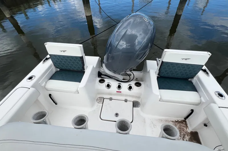 Slide: The Image of 2021 Tidewater 198 CC Adventure boat interior with seating and motor, docked on calm water. - 10