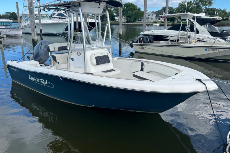Slide: The Image of 2021 Tidewater 198 CC Adventure boat docked in a marina, featuring sleek design and blue hull. - 1
