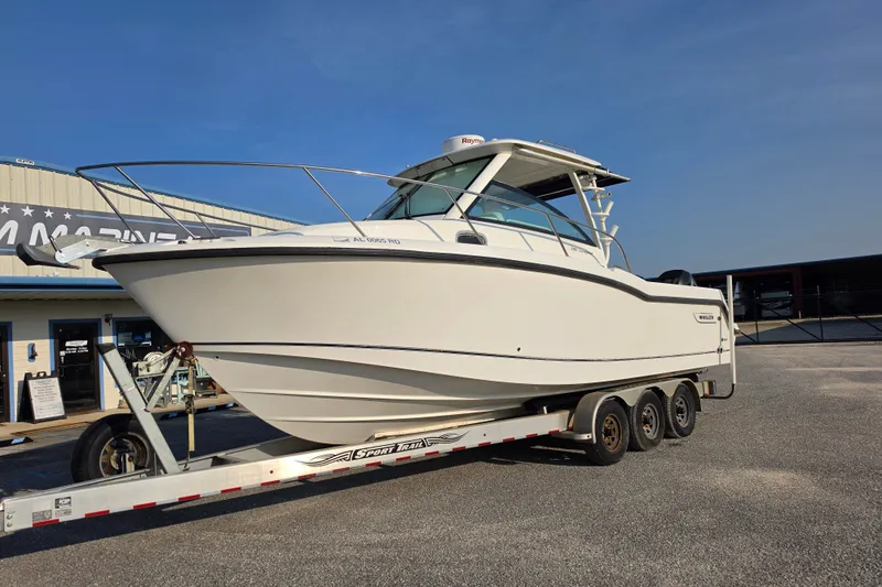 Slide: The Image of 2012 Boston Whaler 285 Conquest boat on trailer, parked outdoors under clear sky. - 3