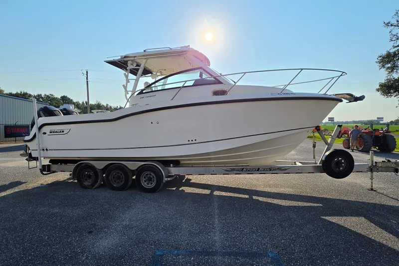 Slide: The Image of 2012 Boston Whaler 285 Conquest boat on trailer, parked outdoors under clear sky. - 6