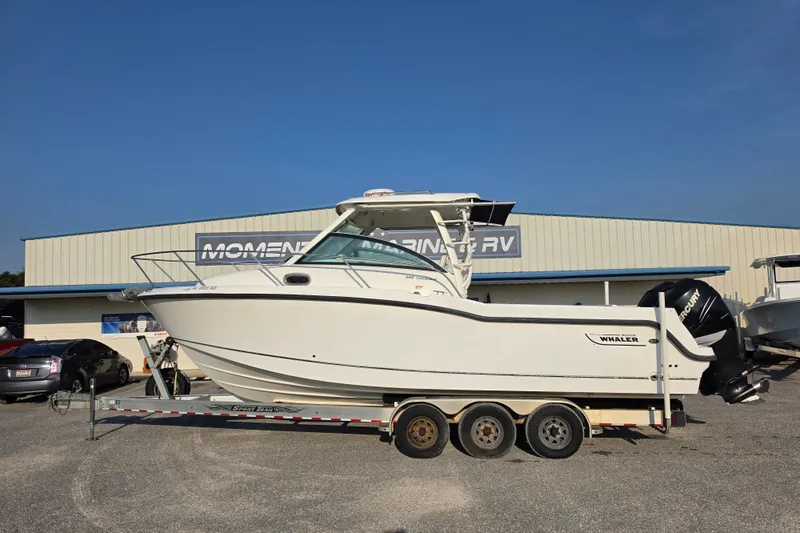 Slide: The Image of 2012 Boston Whaler 285 Conquest boat on trailer, parked outside marine dealership. - 0