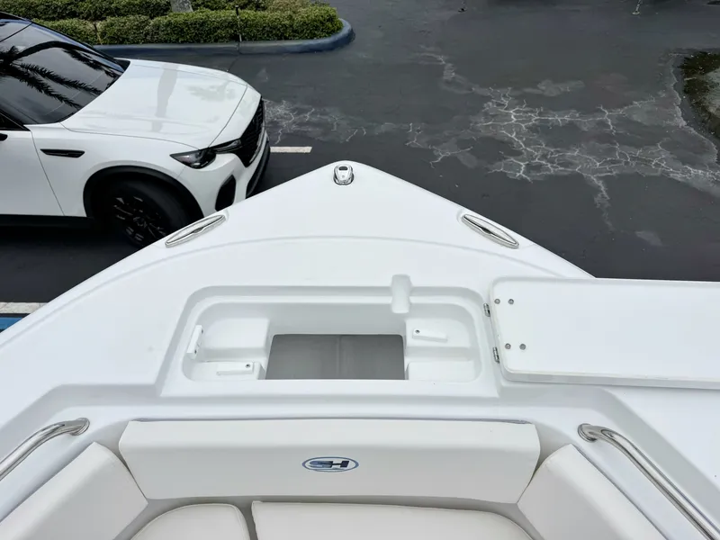 Slide: The Image of The image shows the bow of a 2027 Sea Hunt Ultra 219 boat parked next to a white car. - 27