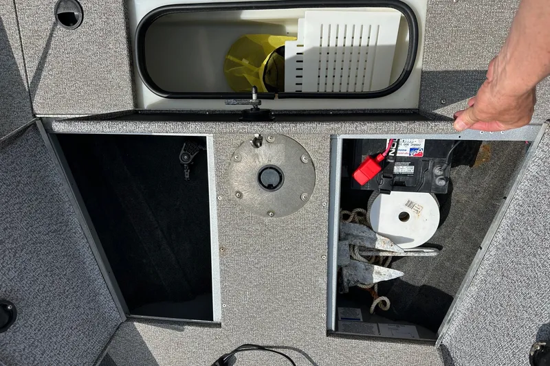 Slide: The Image of 2021 Alumacraft Classic 165 CS boat storage compartments with battery and anchor. - 13