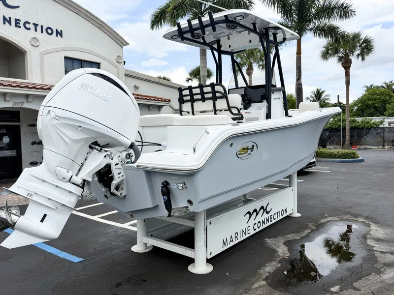 Slide: The Image of A 2027 Sea Hunt Ultra 219 boat on a white stand in front of a building with palm trees. - 8