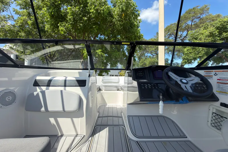 Slide: The Image of 2023 Bayliner VR5 Bowrider OB interior with steering wheel and seating, under clear blue sky. - 14