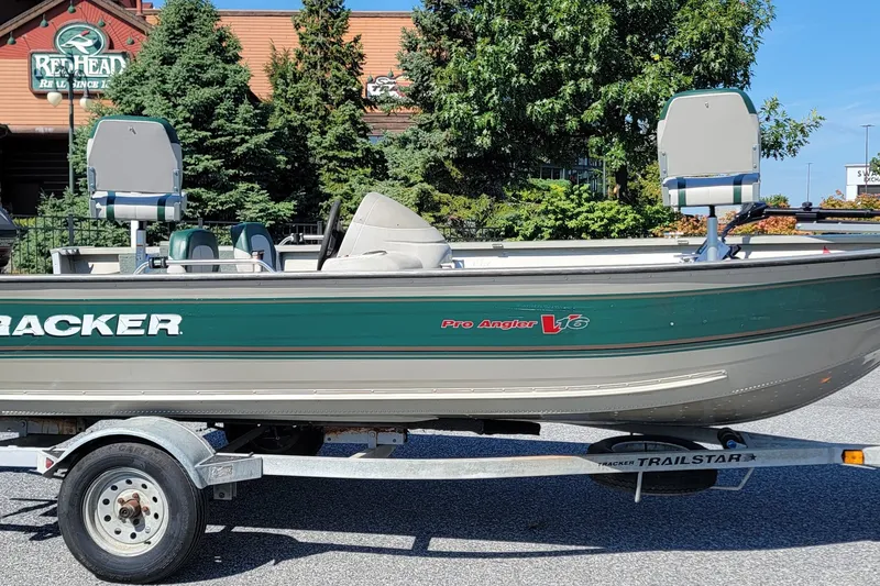 The Image of 2000 Tracker Pro Angler V 16 boat on trailer, parked outdoors near trees. - 1