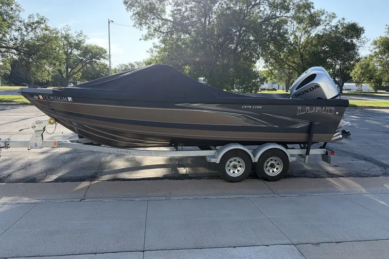 The Image of 2021 Lund 1975 Tyee boat on trailer with cover, parked outdoors. - 1