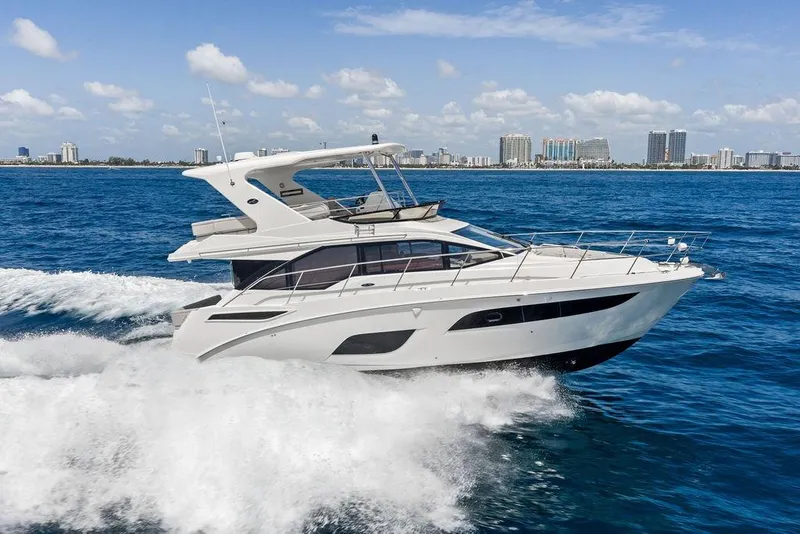 Slide: The Image of 2018 Sea Ray Fly 460 cruising on the ocean with a city skyline in the background. - 7