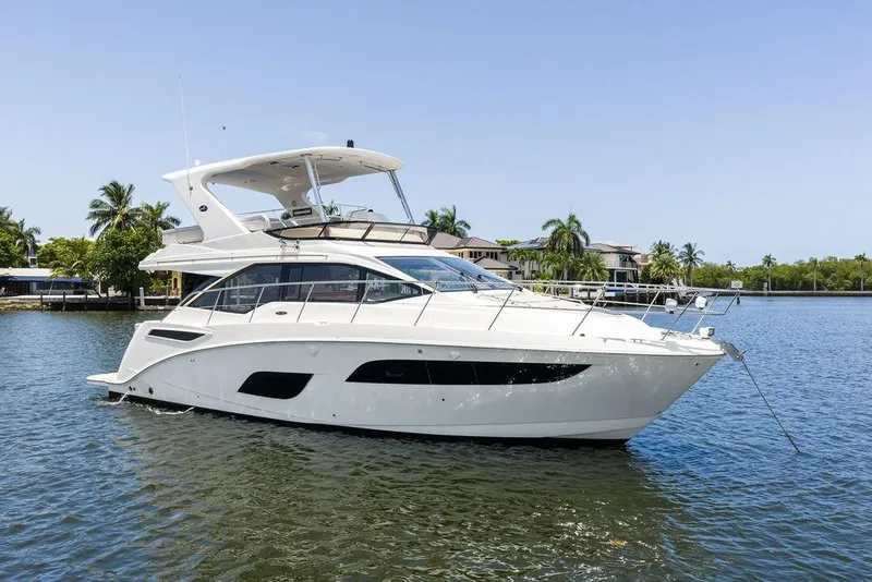 Slide: The Image of 2018 Sea Ray Fly 460 yacht on calm water, surrounded by palm trees and waterfront homes. - 10
