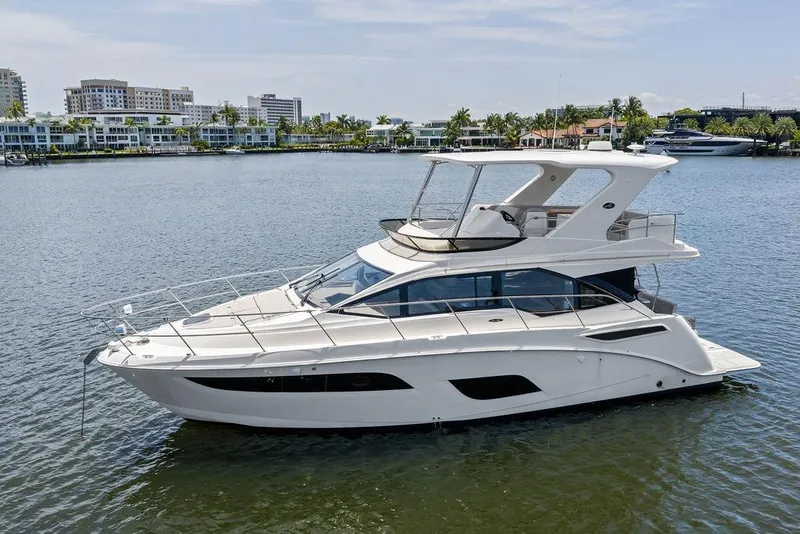Slide: The Image of Un Sea Ray Fly 460 de 2018 en aguas tranquilas, rodeado de edificios modernos y palmeras. - 17