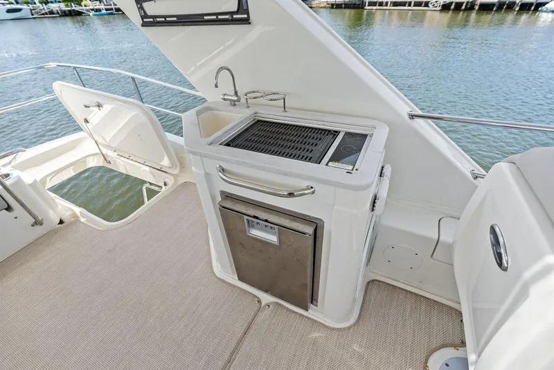 Slide: The Image of The 2018 Sea Ray Fly 460 features an outdoor kitchenette with a sink and grill. - 44