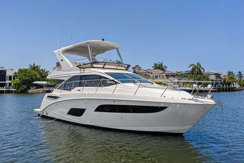 Slide: The Image of 2018 Sea Ray Fly 460 yacht on calm water, with luxury waterfront homes in the background. - 20
