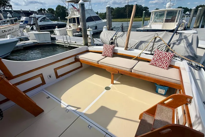 Slide: The Image of 1987 Wilbur Flybridge Cruiser with cushioned seating, docked at a marina under a clear sky. - 16