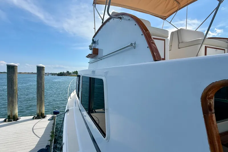 Slide: The Image of 1987 Wilbur Flybridge Cruiser docked by calm waters under a clear blue sky. - 20