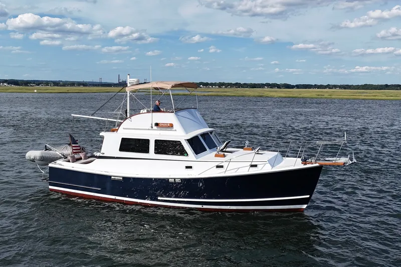 Slide: The Image of 1987 Wilbur Flybridge Cruiser on open water under a partly cloudy sky. - 6