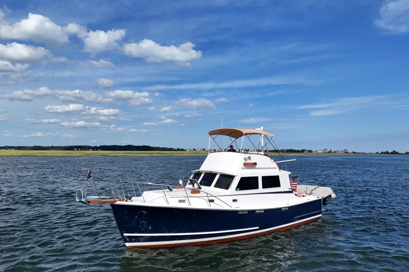 Slide: The Image of 1987 Wilbur Flybridge Cruiser on calm water under a clear blue sky. - 2