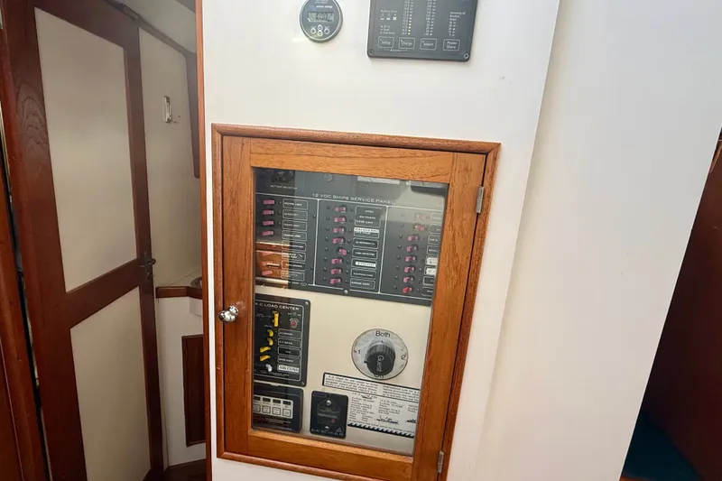 Slide: The Image of Electrical panel inside 1987 Wilbur Flybridge Cruiser, featuring wooden frame and control switches. - 48
