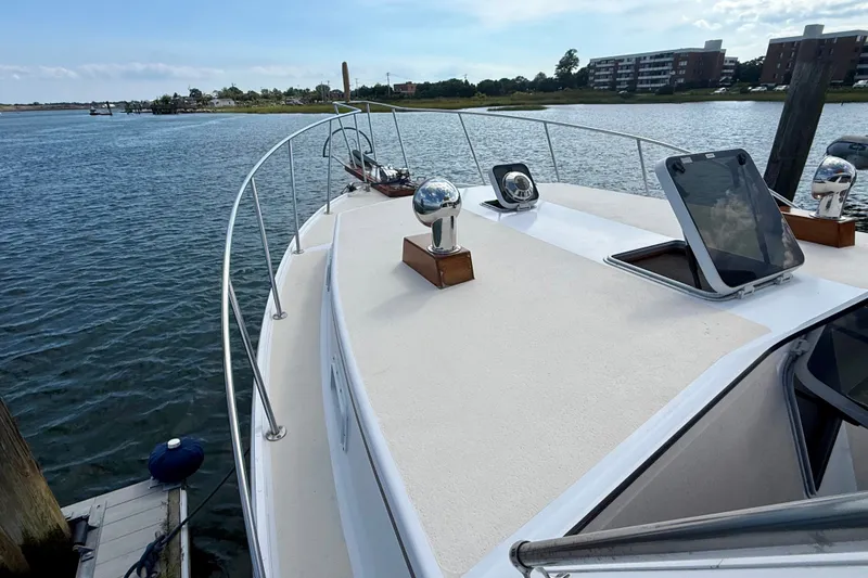 Slide: The Image of 1987 Wilbur Flybridge Cruiser docked by calm waters, showcasing deck and railing. - 21