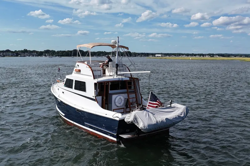 Slide: The Image of 1987 Wilbur Flybridge Cruiser on calm waters under a partly cloudy sky. - 4