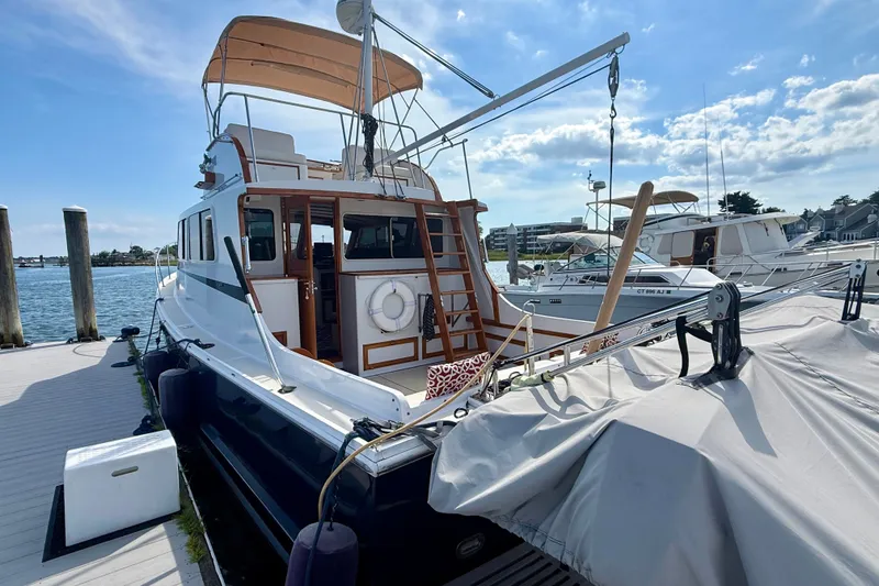 Slide: The Image of 1987 Wilbur Flybridge Cruiser docked at marina under clear blue sky. - 11