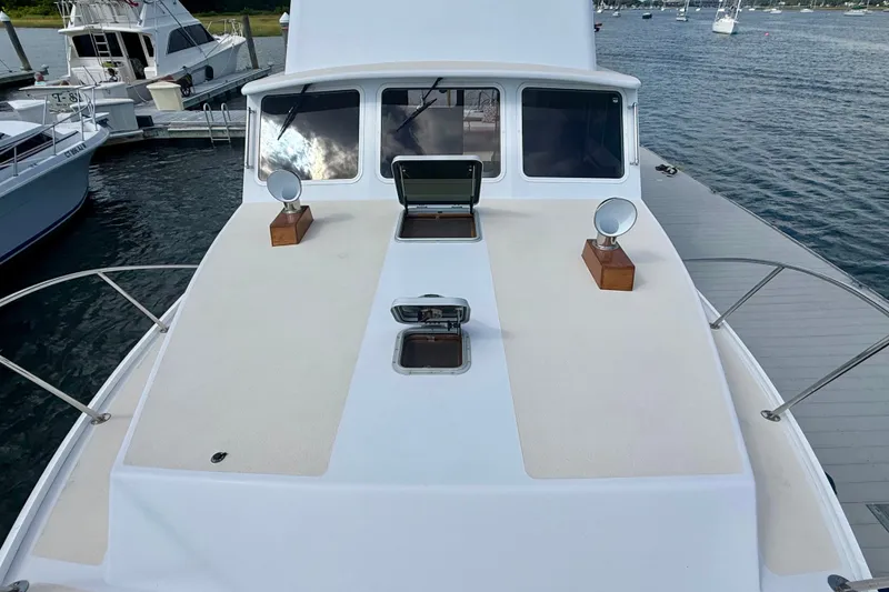 Slide: The Image of 1987 Wilbur Flybridge Cruiser docked, showcasing deck and windows with scenic water backdrop. - 26