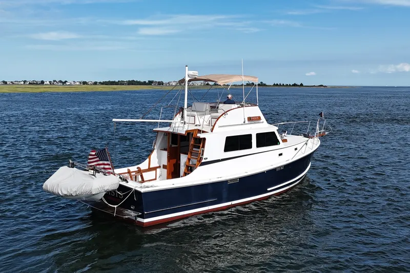 Slide: The Image of 1987 Wilbur Flybridge Cruiser on open water, featuring classic design and American flag. - 7