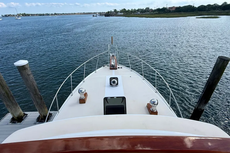 Slide: The Image of 1987 Wilbur Flybridge Cruiser docked, overlooking serene waters and distant shoreline. - 36