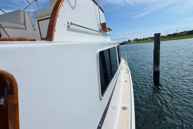 Slide: The Image of 1987 Wilbur Flybridge Cruiser on calm water, showcasing sleek design and wooden accents. - 19