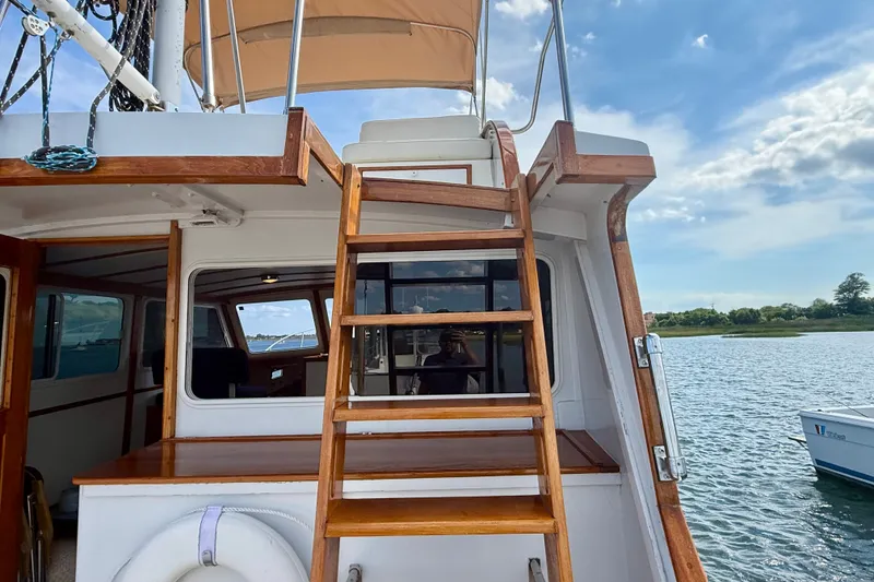Slide: The Image of 1987 Wilbur Flybridge Cruiser with wooden ladder, docked on a serene lake. - 30