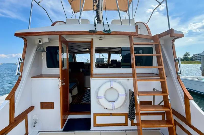 Slide: The Image of 1987 Wilbur Flybridge Cruiser with wooden ladder and life preserver, docked by the water. - 15
