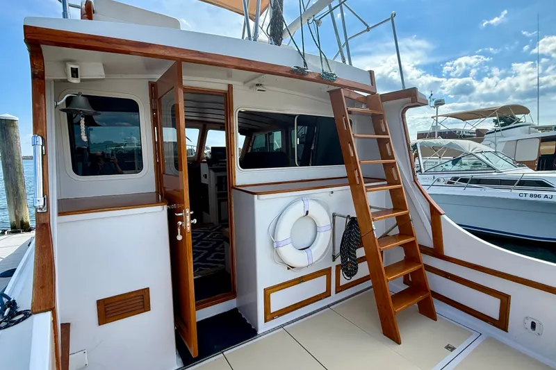 Slide: The Image of 1987 Wilbur Flybridge Cruiser with wooden ladder and life preserver, docked at marina. - 14