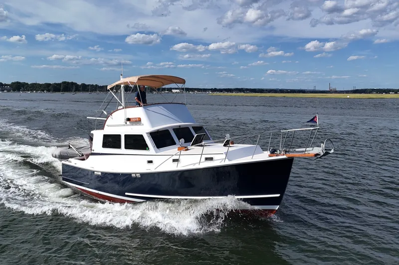 The Image of 1987 Wilbur Flybridge Cruiser navigating calm waters under a clear blue sky. - 0